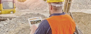 A construction worker reviews our website on tablet at a construction site.